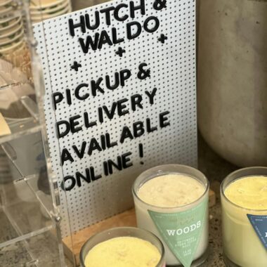 A sign promotes pickup and delivery options at a candle store.